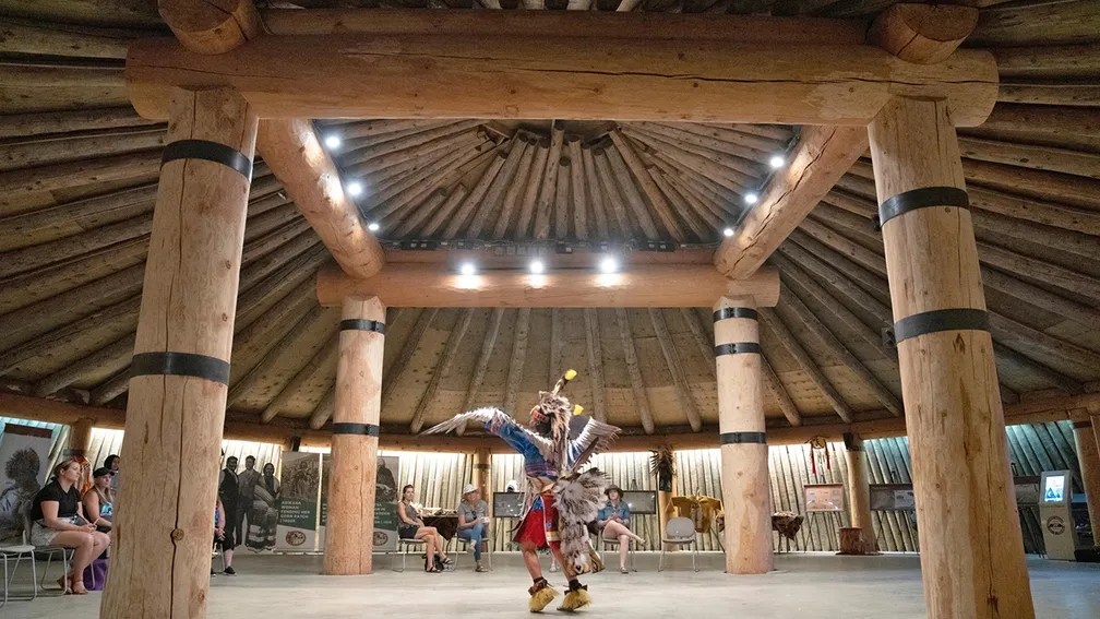 Visitors watch a cultural performance at MHA Nation Earthlodge Village in North Dakota, an immersive setting where guests can learn traditions, stories, and community history through live programming.